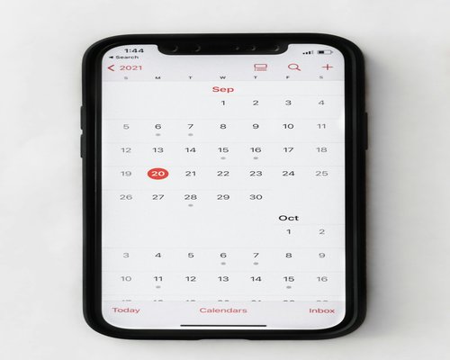 A smartphone displaying a calendar next to a cup of coffee
