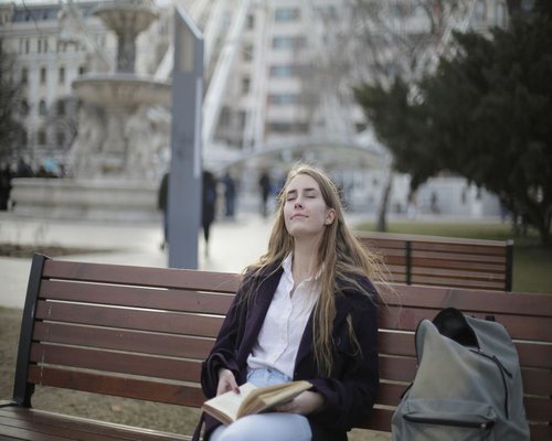 Person resting eyes while sitting on a park bench
