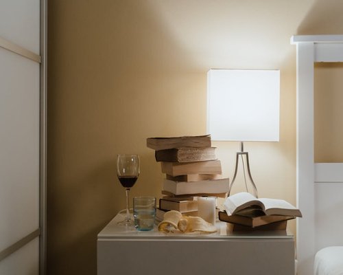 A bedside table with a warm yellow reading lamp and an open book