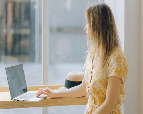 Person looking away from a computer screen out the window